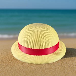 Peut inclure: Un chapeau de paille jaune avec un ruban rouge est posé sur le sable. Le chapeau a une couronne arrondie et un large bord. L'arrière-plan montre la mer et un ciel bleu, suggérant une journée ensoleillée.