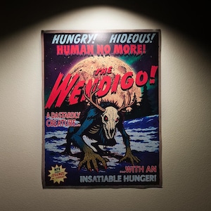 May include: A vintage-style poster featuring a monstrous Wendigo creature with antlers and a skull-like head. The poster has a dark color scheme with the words "HUNGRY! HIDEOUS! HUMAN NO MORE!" and "THE WENDIGO!" in bold text. The poster is mounted on a wall.