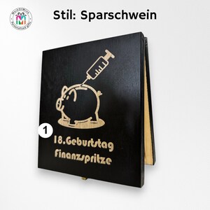 May include: Black wooden piggy bank with a laser-etched design. The design features a pig with a syringe, and the text "18. Geburtstag finanzspritze". The bank is a personalized gift.