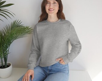 May include: A gray sweatshirt with long sleeves and a crew neck. The left sleeve has the text "Always Be Kind" written vertically in black.