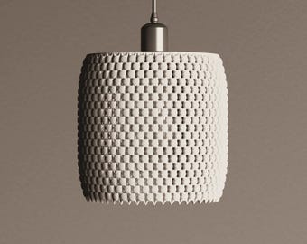 May include: A white, cylindrical pendant light fixture with a textured, woven pattern. The light hangs from a silver-colored rod and cap. The shade has a series of small, rectangular openings, creating a unique design. The overall aesthetic is modern and minimalist.