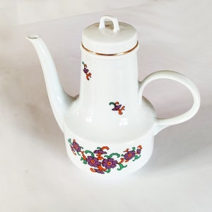 Puede incluir: Tetera de cerámica blanca con ribete dorado y diseño floral morado y naranja.
