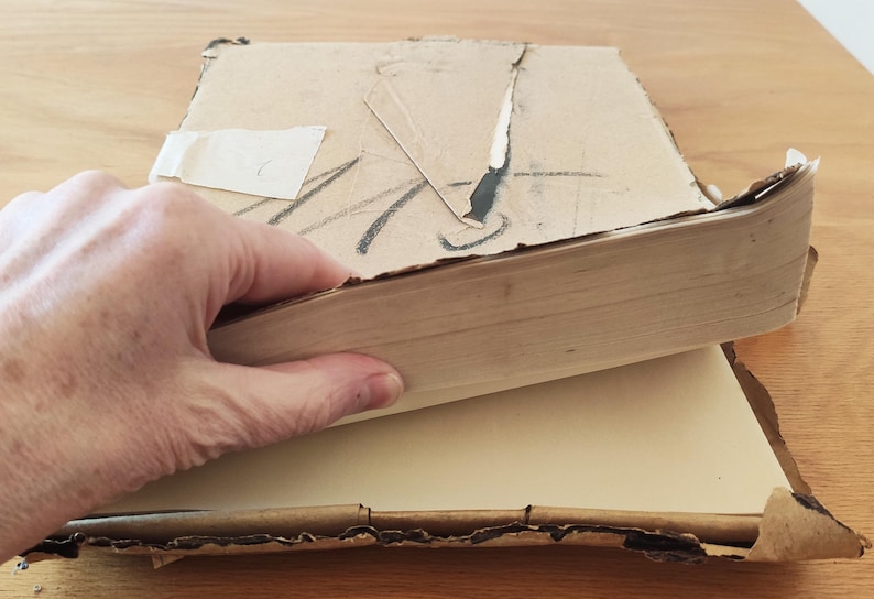 Puede incluir: Un libro vintage con una cubierta de cart&oacute;n marr&oacute;n y un interior de papel blanco. El libro est&aacute; ligeramente da&ntilde;ado y tiene un trozo de cinta adhesiva en la cubierta.