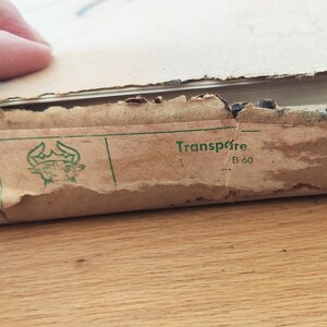 Puede incluir: Primer plano de una caja de cart&oacute;n marr&oacute;n con una etiqueta verde que dice "Transpa&iuml;re B 60". La etiqueta tambi&eacute;n presenta una ilustraci&oacute;n verde de una cabeza de toro.