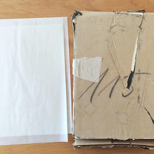 Puede incluir: Una pila de cajas de cart&oacute;n con una hoja de papel blanca en la parte superior. Las cajas de cart&oacute;n son marrones y tienen algo de escritura en ellas.