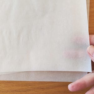 Puede incluir: Una pila de papel vegetal blanco, a menudo utilizado para hornear o manualidades.