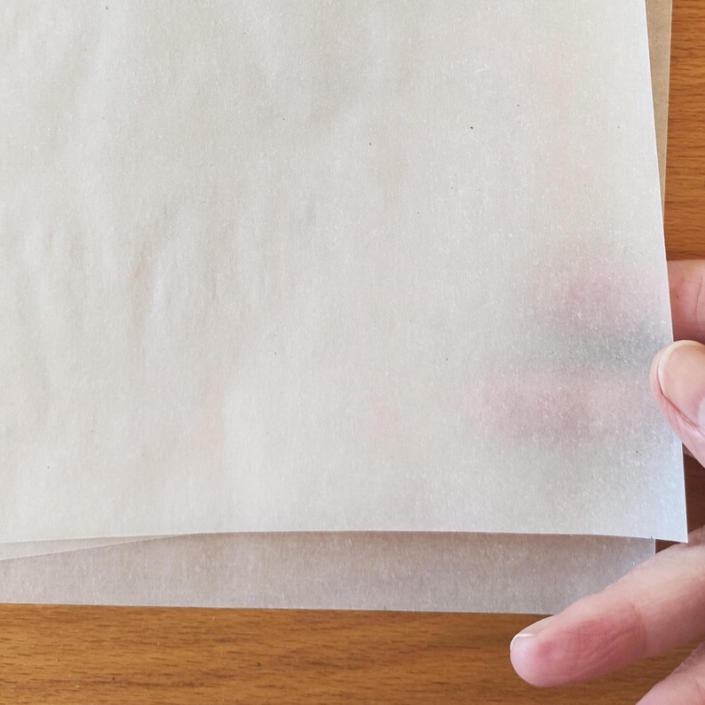 Puede incluir: Una pila de papel vegetal blanco, a menudo utilizado para hornear o manualidades.