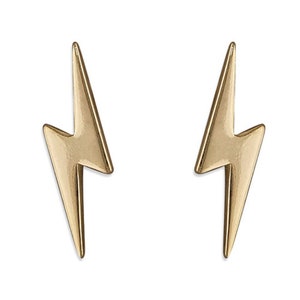 Könnte beinhalten: Ein Paar goldfarbene Blitz-Ohrstecker. Die Ohrringe sind symmetrisch, mit einer spitzen Spitze und gezackten Kanten, vor weißem Hintergrund. Die Ohrringe sind ein schlichtes, aber auffälliges Accessoire.