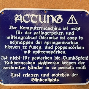 May include: A blue sign with white text that reads "ACHTUNG!"  The sign warns against touching or tampering with the computer machine. It says "Der Komputermaschine ist nicht für der gefingerpoken und mittengraben! Oderwise ist easy to schnappen der springenwerken, blowen ze fusen, und poppencörken mit spitzenspärken. Ist nicht für gewerken bie Dumköpfen! Rubbernecken sighteeren keepen der verdamten händer in ze pockets müß. Just relaxen und watchen der Blinkenlights."