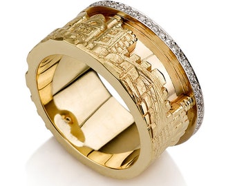 May include: A gold ring with a detailed cityscape design. The ring features a textured, three-dimensional relief of buildings and structures. A band of small, clear stones encircles the top edge of the ring, adding a touch of sparkle.