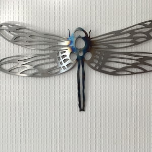May include: A metal dragonfly wall decoration with intricate details and a blue-grey finish.