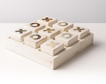 Gioco del tris in legno sbiancato, pezzi placcati in oro, arredamento moderno.