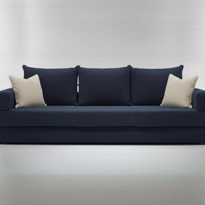May include: A navy blue sofa with three back cushions and two cream-colored throw pillows. The sofa has a textured, ribbed fabric. The design is modern and minimalist, suitable for a living room or lounge area.