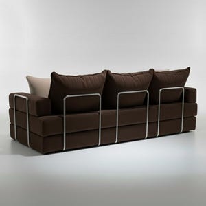 May include: A modern brown sofa with three large, square cushions and a light-colored pillow. The sofa has a low profile and a metal frame. The cushions are a dark brown color.