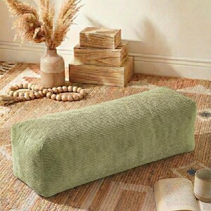 Może przedstawiać: Prostokątny puf z sztruksu w kolorze szałwii. Puf stoi na wzorzystym dywanie, z wazonem z suszonymi kwiatami, drewnianymi pudełkami i książką w pobliżu. Paleta kolor&oacute;w jest neutralna i ziemista.