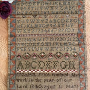 May include: Antique sampler with embroidered letters, numbers, and decorative borders. The text reads "Elizabeth Price finished this work in the year of our Lord 1840, aged 11 years." The sampler is in shades of brown, red, and green.