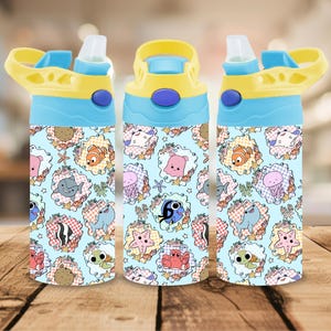 Puede incluir: Tres botellas de agua con un fondo azul claro y un patrón repetido de criaturas marinas de dibujos animados. Las botellas tienen tapas amarillas y azules con una boquilla abatible. Las criaturas marinas incluyen peces, tiburones y medusas.