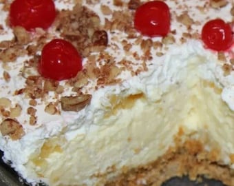 May include: A dessert layered with graham cracker crust, vanilla pudding, whipped cream, and chopped pecans, topped with maraschino cherries.
