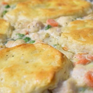 Può includere: Una pirofila piena di un cremoso composto di pollo e verdure ricoperto da biscotti dorati.