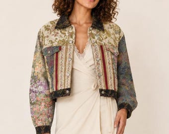 May include: A cropped jacket featuring a multi-colored floral tapestry pattern with vertical striped panels, worn over a cream-colored wrap dress with lace trim. The outfit is completed with matching floral tapestry ankle boots with block heels.