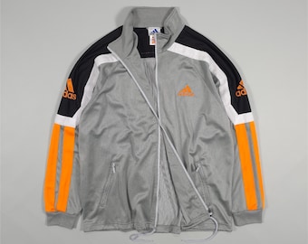 Chaqueta deportiva Adidas de los 90: bloques de color plateado, negro y naranja con rayas anchas. Talla L. Talla M y L.