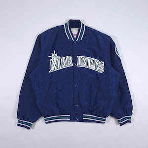May include: A navy blue satin jacket with the text "MARINERS" in white across the chest. The jacket has a button-up front, a white, teal, and navy striped collar and cuffs, and a team logo on the sleeve.