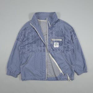 Könnte beinhalten: Hellblaue Jacke mit durchgehendem Reißverschluss, zwei Vordertaschen und einer kleinen Brusttasche. Die Jacke hat einen hohen Kragen und einen Kordelzug am Saum. Der Stoff hat ein dezentes Streifenmuster und ein kleines Logo-Patch.