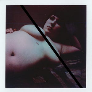 May include: A Polaroid-style photograph featuring a person lying down, with a black diagonal line across the image. The person's torso is visible, with a focus on the chest and abdomen. The image has a vintage, slightly faded aesthetic.