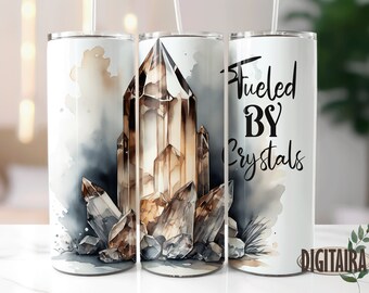 Può includere: Un bicchiere bianco con un design ad acquerello di cristalli marroni e il testo "Fueled By Crystals".