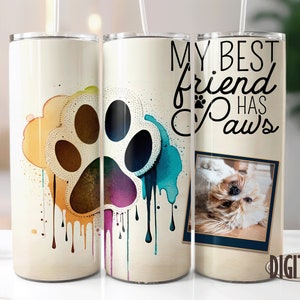 May include: A set of three stainless steel tumblers with a paw print design and the text "My best friend has paws". One tumbler features a colorful paw print with dripping paint, another has a photo of a dog, and the third has the text.