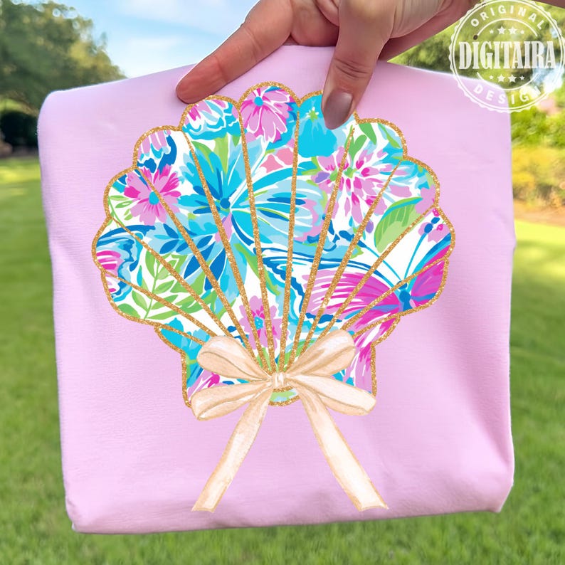May include: A light pink tote bag featuring a seashell design. The seashell is filled with a colorful floral pattern in shades of blue, pink, and green, outlined with gold glitter. A beige bow is at the bottom of the seashell.