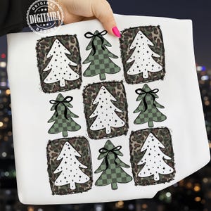 Può includere: Tessuto bianco con un motivo ripetuto di alberi di Natale. Alcuni alberi sono bianchi con pois neri, altri sono verdi a scacchi e tutti sono incorniciati in stampa leopardata. Ogni albero ha un fiocco nero in cima. Il disegno è tenuto da una persona.