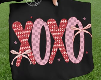 Puede incluir: Bolso tote negro con las letras XOXO en patrones rosas y rojos. Las X tienen un patrón de diamantes rojos y las O tienen un patrón de tablero de ajedrez rosa. Lazos rosas y estrellas adornan el diseño.