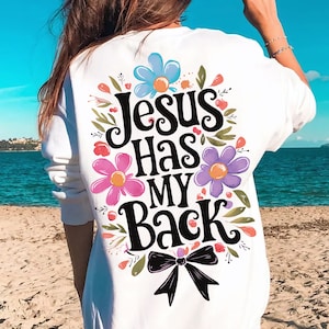 May include: White sweatshirt with a floral design and the text "Jesus Has My Back" in black lettering. A black bow is at the bottom of the design.