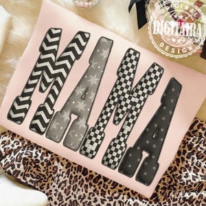 May include: A pink cushion displaying the word "MAMA" in large, patterned letters. The letters feature black and white chevron, snowflakes, checkered, and star designs. The cushion rests on a leopard print fabric.