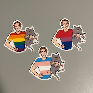 May include: Three sticker designs featuring a person with a different coloured pride flag shirt holding a small grey animal. The first sticker has a rainbow flag shirt, the second has a bisexual flag shirt, and the third has a transgender flag shirt.