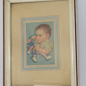 May include: Framed vintage print of a baby holding a stuffed bunny. The artwork features soft pastel colors, a light blue background, and a cream-colored mat. The frame is white with a distressed finish.