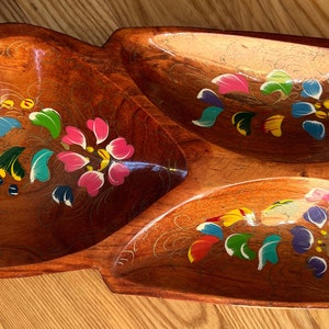 May include: A wooden serving dish with three sections, each painted with colorful floral designs. The dish is brown and has a natural wood grain.