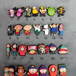 May include: A selection of colourful cartoon character shoe charms. The charms feature characters from various animated shows, including Courage the Cowardly Dog, Shrek, and South Park. Some charms have the word "LAME" on them.