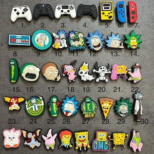 May include: A selection of vibrant shoe charms with diverse designs. The collection includes video game controllers, cartoon characters such as Rick and Morty, SpongeBob, and other pop culture icons. These charms are designed to be attached to shoes.