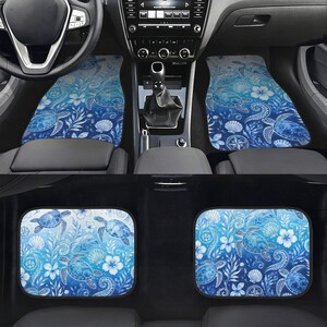 May include: A set of four car floor mats featuring a blue and white gradient pattern with illustrations of sea turtles, seashells, tropical flowers, and coral reef foliage. The design displays a repeating aquatic theme across all four rectangular mats.