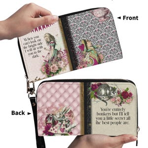Puede incluir: Una cartera con cremallera con ilustraciones de Alicia en el país de las maravillas. La parte delantera presenta un diseño floral y estampado con una cita. La parte trasera tiene un patrón acolchado rosa y una cita con una ilustración de conejo blanco. La cartera está abierta.