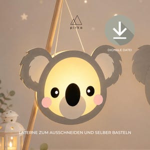 May include: A koala-shaped lantern craft template featuring a grey outline, a light-coloured face, black eyes and nose, and pink cheeks. The design includes the text pirka, a download icon, and the German text LATERNE ZUM AUSSCHNEIDEN UND SELBER BASTELN.