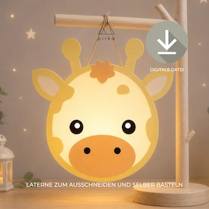 Könnte beinhalten: Eine gelb-cremefarbene Giraffen-Papierlaterne zum Ausschneiden, hängend an einem Holzständer. Das Design zeigt ein Giraffengesicht mit braunen Flecken, schwarzen Augen und beigem Maul. Text: 'pirka', 'DIGITALE DATEI', 'LATERNE ZUM AUSSCHNEIDEN UND SELBER BASTELN'.