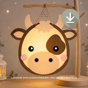 May include: A cow-shaped paper lantern craft featuring a cream-colored face, dark brown ears and horns, a dark brown eye patch, and pink cheeks. The design includes the text pirka, a download icon, and the text DIGITALE DATEI.
