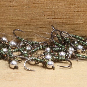 May include: A group of green and silver fly fishing lures with feathered tails.