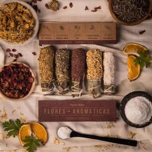 May include: A set of five smudge sticks with different flower and herb blends. The sticks are wrapped in brown paper and tied with twine. The box is labeled "Flores Aromáticas" and "Sahumerios Surtidos".