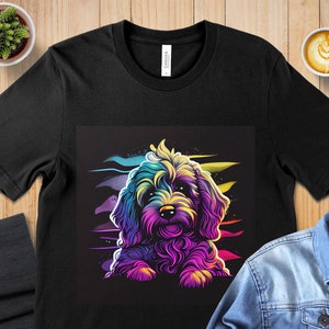 May include: A black t-shirt with a colorful graphic of a fluffy dog with a rainbow-colored fur. The dog is looking at the viewer with a playful expression.