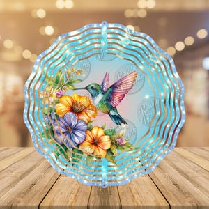 May include: A blue metal wind spinner with a hummingbird and flowers. The hummingbird is flying with its wings spread. The flowers are yellow, pink, and purple.