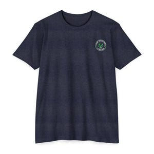 Op de afbeelding: Marineblauw T-shirt met korte mouwen en een ronde hals. Het shirt heeft een cirkelvormig logo op de linkerborst met de tekst "Liam Maguire's Irish Pub" in groen en wit. Het T-shirt is gemaakt van een zachte, getextureerde stof.